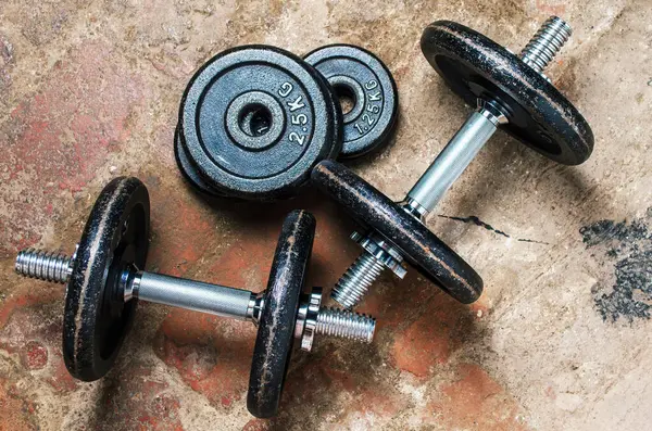 Dambıllar ve ağırlık plakaları kaba tuğla zeminde yan açıdan bakıldığında