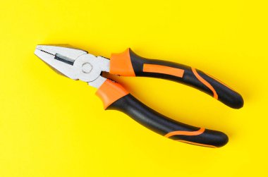 Parlak sarı arka plan görünümünde kauçuk saplı metal pense aracı
