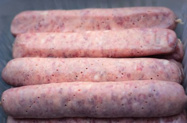 Çiğ Bavyera sosisleri ızgara için hazır. Tepside taze et dokusunu yakından gösteriyor.