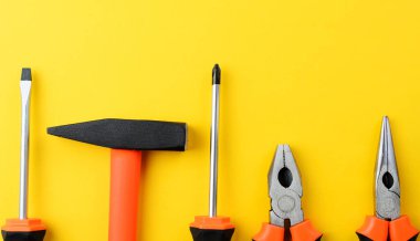 Sarı arkaplan, tornavida, çekiç, boş kopya alanı olan pense ipuçları