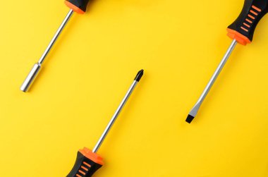 Üç tornavida kısmen sarı arkaplan üzerinde boş alan ve minimal araç düzeni ile görünür