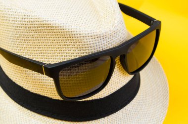 Güneş gözlüklü klasik erkek şapkası. Önden sarı arka plana yerleştirilmiş.