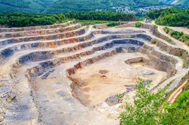 Yeşil tepelerle çevrili yollar ve katmanlı bir çukur mayını.