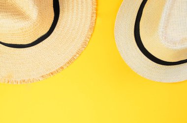 Sarı arka planda iki yaz plaj şapkasının üst görüntüsü
