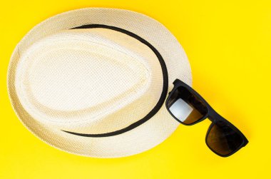 Sarı arka planda şapka ve güneş gözlüğü yaz tatili seyahat moda konsepti