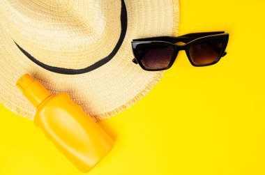 Sarı arka planda güneş gözlüğü ve güneş kremi yaz tatili konsepti