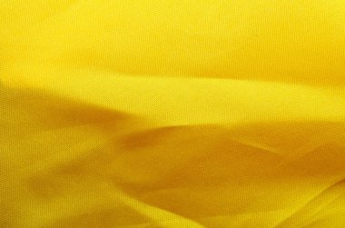Yumuşak kıvrımlı parlak sarı kumaş ve titreyen doku dinamik arkaplan oluşturur