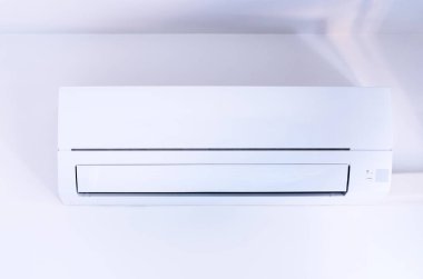 Duvara monte edilmiş modern beyaz klima içeride soğutma ve konfor sağlıyor.