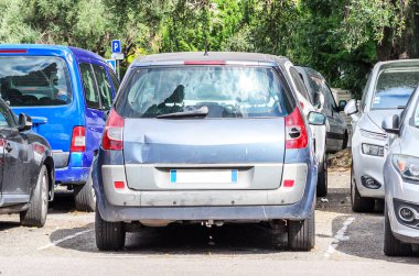 Gümüş bir arabanın arka tarafında görünür bir göçük var. Araç gövdesinde hasar var.