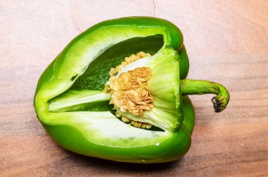 Büyük yeşil dolmalık biber. Köy ahşap arka planına yerleştirilmiş tohumlarla açılmış..