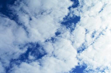 Pofuduk beyaz bulutların sürüklendiği huzurlu mavi bir gökyüzü.