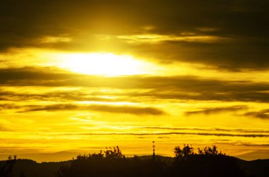 Yoğun Altın Gün batımı Tepelerin Üzerinde Dramatik Siluetli Manzara ve Bulutlarla