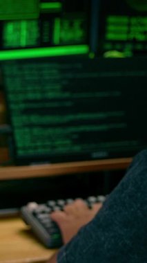 Parlak yeşil monitörlü bilgisayar korsanının iş yerindeki dikey videosu