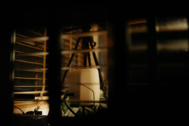 Pencere perdelerinden sinema masasına sessiz ve samimi bir bakış. Yumuşak, ılık ışıklar ve bulanık çizgiler nostaljik ve yansıtıcı bir atmosferi çağrıştırıyor..