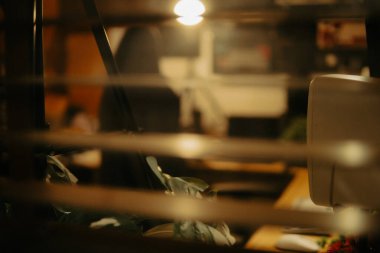 Pencere perdelerinden sinema masasına sessiz ve samimi bir bakış. Yumuşak, ılık ışıklar ve bulanık çizgiler nostaljik ve yansıtıcı bir atmosferi çağrıştırıyor..