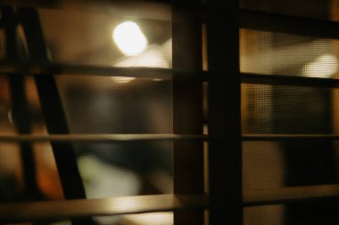 Pencere perdelerinden sinema masasına sessiz ve samimi bir bakış. Yumuşak, ılık ışıklar ve bulanık çizgiler nostaljik ve yansıtıcı bir atmosferi çağrıştırıyor..