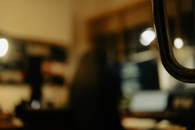 Pencere perdelerinden sinema masasına sessiz ve samimi bir bakış. Yumuşak, ılık ışıklar ve bulanık çizgiler nostaljik ve yansıtıcı bir atmosferi çağrıştırıyor..