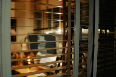 Pencere perdelerinden sinema masasına sessiz ve samimi bir bakış. Yumuşak, ılık ışıklar ve bulanık çizgiler nostaljik ve yansıtıcı bir atmosferi çağrıştırıyor..