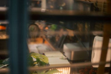 Üç monitör, not defteri, mikrofon ve yeşil bitkilerden oluşan sıcak ve rahat bir masa düzeni. Yaratıcı işler için minimalist bir Japon estetiğine sahip..