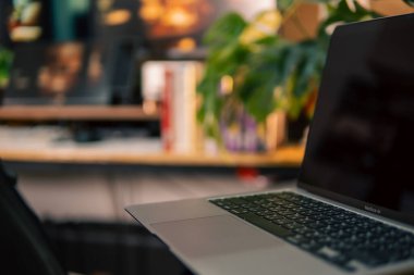 Üç monitör, not defteri, mikrofon ve yeşil bitkilerden oluşan sıcak ve rahat bir masa düzeni. Yaratıcı işler için minimalist bir Japon estetiğine sahip..