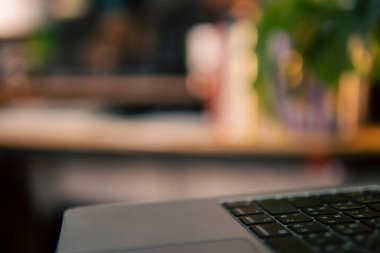 Üç monitör, not defteri, mikrofon ve yeşil bitkilerden oluşan sıcak ve rahat bir masa düzeni. Yaratıcı işler için minimalist bir Japon estetiğine sahip..