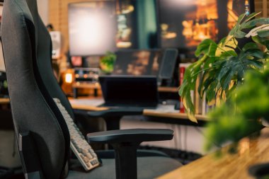 Üç monitör, not defteri, mikrofon ve yeşil bitkilerden oluşan sıcak ve rahat bir masa düzeni. Yaratıcı işler için minimalist bir Japon estetiğine sahip..