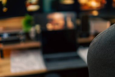 Üç monitör, not defteri, mikrofon ve yeşil bitkilerden oluşan sıcak ve rahat bir masa düzeni. Yaratıcı işler için minimalist bir Japon estetiğine sahip..