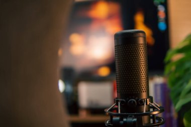 Üç monitör, not defteri, mikrofon ve yeşil bitkilerden oluşan sıcak ve rahat bir masa düzeni. Yaratıcı işler için minimalist bir Japon estetiğine sahip..