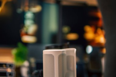 Üç monitör, not defteri, mikrofon ve yeşil bitkilerden oluşan sıcak ve rahat bir masa düzeni. Yaratıcı işler için minimalist bir Japon estetiğine sahip..