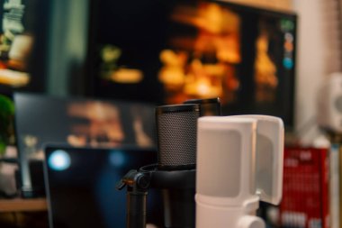 Üç monitör, not defteri, mikrofon ve yeşil bitkilerden oluşan sıcak ve rahat bir masa düzeni. Yaratıcı işler için minimalist bir Japon estetiğine sahip..