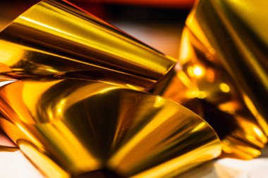 Dinamik kıvrımları ve yansımaları olan parlak altın folyonun yüksek çözünürlüklü yakın çekimi. Lüks markalaşma, paketleme veya dijital tasarım projelerinde kullanmak için zarif metalik dokuyu yakalar.