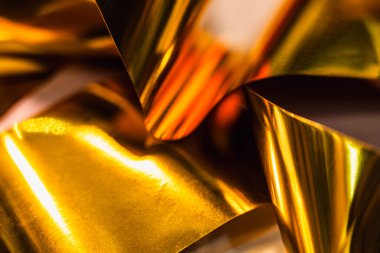 Dinamik kıvrımları ve yansımaları olan parlak altın folyonun yüksek çözünürlüklü yakın çekimi. Lüks markalaşma, paketleme veya dijital tasarım projelerinde kullanmak için zarif metalik dokuyu yakalar.