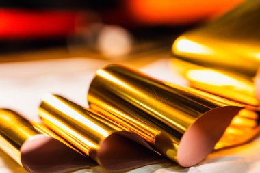 Dinamik kıvrımları ve yansımaları olan parlak altın folyonun yüksek çözünürlüklü yakın çekimi. Lüks markalaşma, paketleme veya dijital tasarım projelerinde kullanmak için zarif metalik dokuyu yakalar.