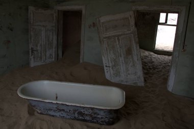 Kum ve denizin olduğu bir çölde terk edilmiş bir bina.