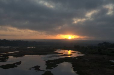 Bulutlu bir gökyüzüyle gölün üzerinde gün doğumu.