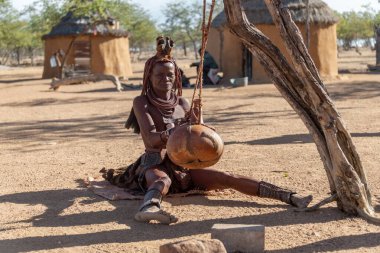 Köyde elinde torbayla ağaçta oturan bir adam.