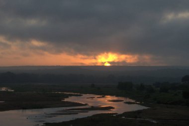 Nehir ve bulutlu gökyüzü olan güzel bir manzara.