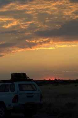 Gün batımının arka planda bir araba ile güzel bir görüntüsü.
