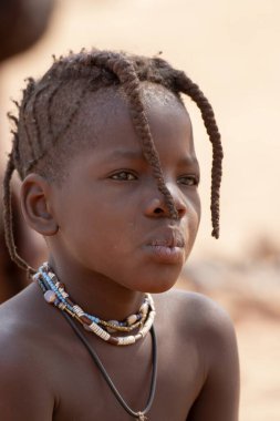 Büyük siyah kolyesi olan genç bir çocuğun portresi.