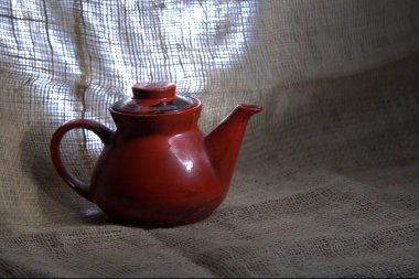Masadaki kırmızı seramik sürahinin yakın plan fotoğrafı.