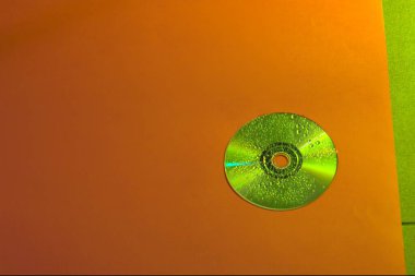 Turuncu arka planda yeşil bir CD 'nin üst görüntüsü