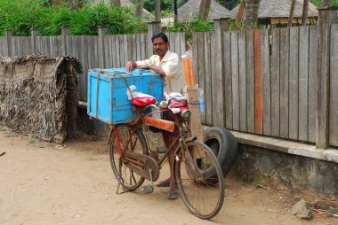 man in a wheelchair with a bicycle in the village