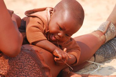 Genç anne çölde bebeğiyle oynuyor.