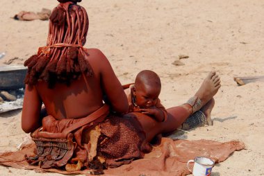 Elbiseli genç bir kadın ve çölde bir çocuk.