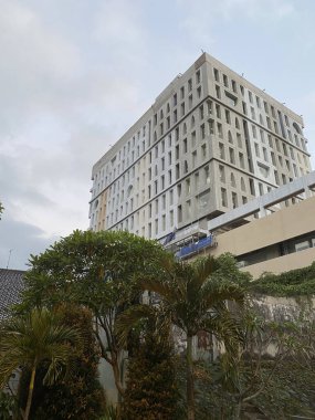 Mavi gökyüzü geçmişi olan yeşil ağaçların arasında bir otel binası..