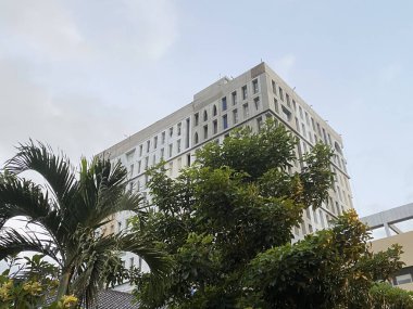 Geometrik pencereleri ve benzersiz bir dış görünüşü olan yüksek katlı beton bir binanın modern mimarisi. Alçak bir açıdan bakıldığında, bina tamamlanmamış..