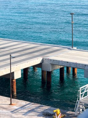 Minimalist bir rıhtım yapısı Karayip Denizi 'nin sakin, berrak turkuaz sularını yumuşak ışık ve gölgelerle kaplar..