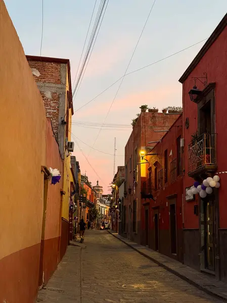 Küçük bir Meksika kasabasında gün batımında turuncu ve kırmızı tonlarda parlayan huzurlu, dar bir yaya sokağı, sömürge mimarisi ile kaplıdır..