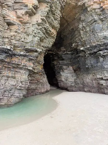 Kayalık kayalıklara oyulmuş doğal bir deniz mağarası turkuaz su ve Playa de las Catedrales, Galiçya 'da yumuşak beyaz kumların yanında bulunur..