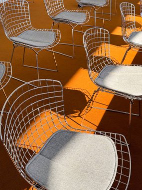 Kalın gölgeli turuncu halıda beyaz sandalyeler